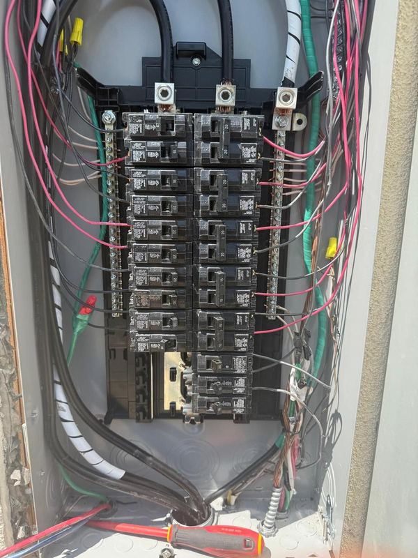 Open electrical panel with new breakers and circuit wires routed along both sides