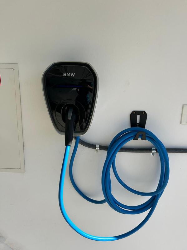 BMW home EV charger with a blue cable hung on a garage wall