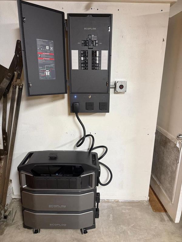 EcoFlow backup panel on a garage wall with its battery stack on the floor below